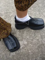 Zapatos negros de cuero con plataforma y costuras blancas.