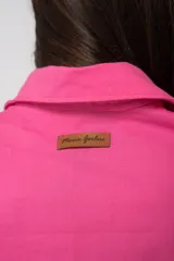 Camisa oversize color fucsia, de lino, con cuello camisero, cierre frontal con botones y mangas largas abullonadas con puños elásticos.