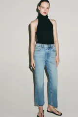 Jeans cropped flare de tiro medio color celeste, confeccionados en denim con efecto lavado. Presentan diseño de cinco bolsillos, trabillas para cinto, raya planchada al frente y bajo desflecado con terminación evasé. Cuenta con cierre frontal de cremallera y botón metálico.