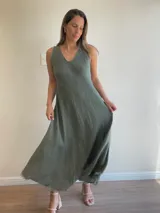 Vestido largo sin mangas, color beige claro, con escote en V y textura arrugada o arrugada, con terminación deshilachada en el ruedo.