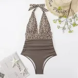 Malla entera combinada con parte superior lisa de color negro, escote halter cruzado y corpiño triangular con copas desmontables. Parte inferior de tiro alto con estampado animal print tipo leopardo.