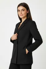 Blazer de corte holgado, color negro, con cuello solapa, cierre frontal con botón y bolsillos laterales.