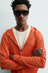 Sudadera con capucha de corte relajado, confeccionada en tejido a rayas horizontales en tonos naranja. Cuenta con cierre frontal de cremallera, cordones ajustables en la capucha y puños y ruedo en rib.