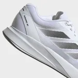 Championes de running Adidas Duramo RC, color blanco con las tres franjas laterales en gris metalizado. Presentan una capellada de malla transpirable y una suela gruesa de EVA blanca con detalles en negro en la parte inferior.