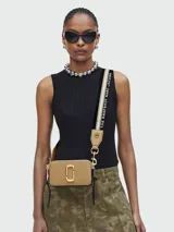 Bolso cruzado Marc Jacobs modelo The Snapshot, color camel, con herrajes dorados y correa ancha intercambiable con texto.