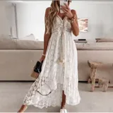 Vestido largo de encaje calado color blanco, con diseño de falda irregular más corta adelante. Presenta escote en V con cordones decorativos y borlas, tirantes finos y detalle de cintura marcada.
