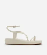 Sandalia tipo flatform color beige, con diseño de tiras finas, dedal metálico en la parte frontal y cierre con hebilla en el talón. Suela plana de altura media.