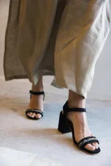 Sandalia de cuero negro, con taco cuadrado y tira delantera adornada con cristales multicolor. Cuenta con tira ajustable en el tobillo.