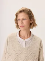 Buzo de lana color marrón topo, con cuello en V y diseño de punto calado en rombos en el frente y mangas.