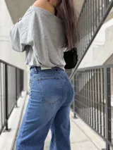 Pantalón de jean azul con corte recto y tiro alto, presenta detalles de tachas metálicas en los bolsillos delanteros.