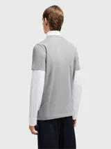 Remera de algodón gris con cuello redondo y logo de la marca estampado en el pecho junto con un pequeño parche circular.