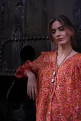 Camisa de seda con estampado floral en tonos naranjas y rosados, de corte amplio y estilo boho. Presenta mangas largas abullonadas, frunces en hombros y espalda, y cierre frontal con botones.