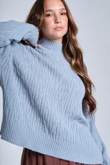 Sweater color crema con cuello alto y diseño de trenzas.