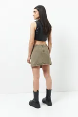 Minifalda de jean celeste con corte asimétrico, bolsillos de parche con solapa y tiras ajustables con hebillas en los laterales.