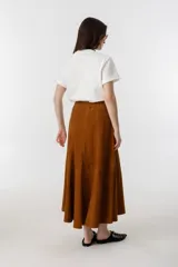 Falda midi de gamuza color marrón, con diseño de corte amplio, tajo lateral y cintura con elástico en la parte trasera. Cuenta con cierre metálico lateral y forro interior.