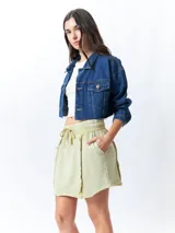 Minifalda color beige con elástico en la cintura, cordones ajustables y costuras marcadas en los laterales.