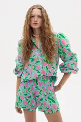 Camisa celeste con estampado floral en tonos rosados y verdes, de lino, con cuello camisero, mangas largas abullonadas y cierre frontal con botones.