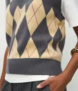 Chaleco de punto corto con diseño de rombos en tonos gris y beige. Presenta escote en V, sisas amplias y terminaciones acanaladas en el ruedo y el cuello.