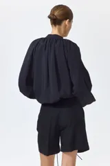 Short negro de tiro alto en mezcla de lino, algodón y viscosa, con pliegues frontales y posteriores, bolsillos al bies y bajos con vuelta cosida.