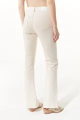 Jean color crudo de tiro medio/alto, silueta levemente acampanada desde la rodilla y tajo en el frente de la pierna.