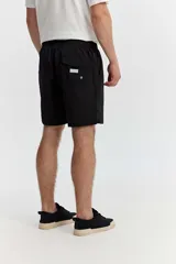 Short de baño bordó liso, de corte largo, con cintura elástica ajustable mediante cordón, bolsillos laterales y un pequeño logo estampado en el lateral.