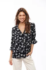 Blusa negra con estampado floral blanco, escote en V y mangas 3/4 con volados.