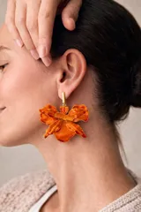 Aros colgantes de gran tamaño con diseño de flor de orquídea en color naranja vibrante, con acabado texturizado y soporte metálico dorado.