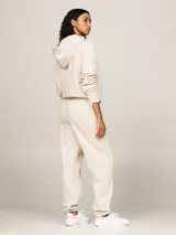 Pantalón de jogging color beige, de corte holgado, con cintura elástica ajustable con cordón y logo bordado en rojo.