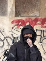 Campera oversize de corderito negro con cierre frontal completo, doble capucha que incluye balaclava integrada y bolsillos ribeteados.