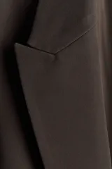 Blazer de sarga con solapas de pico, diseño de frente abierto y bolsillos delanteros con solapa. Presenta mangas con forro a rayas diseñado para ser remangado.