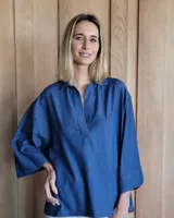 Blusón de denim oscuro con cuello camisero y escote en V, de corte holgado y mangas tres cuartos anchas.