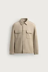 Sobrecamisa relaxed fit color beige con tejido elástico, cuello solapa, manga larga con puños abotonados, bolsillos de plastrón con solapa en el pecho, bolsillos laterales de vivo en la cadera y cierre frontal de botones.