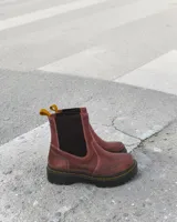 Botín tipo Chelsea de cuero color bordó, con elásticos laterales oscuros, costuras reforzadas en contraste y suela track gruesa con detalle de pespunte amarillo.