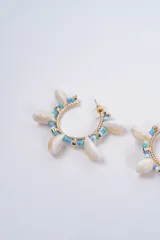 Aros tipo argolla decorados con cuentas de colores fucsia y rosa, intercaladas con pequeñas caracolas naturales y detalles metálicos dorados.