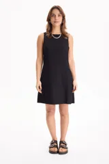 Vestido corto negro sin mangas, de corte recto y holgado, con cuello redondo y bolsillos laterales invisibles.