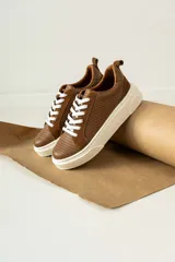 Zapatillas urbanas de cuero color marrón con textura acanalada, cordones blancos y suela de goma blanca.