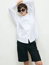 Camisa blanca de corte clásico, con cuello camisero y cierre frontal con botones.