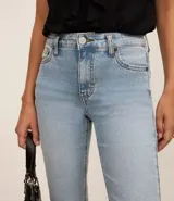 Pantalón bootcut de jeans con elastano, tiro alto, bolsillos delanteros y traseros, y cierre con botón.
