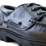 Zapato náutico de cuero color marrón con cordones, detalle de costuras en contraste y suela de goma.