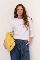 Remera blanca de manga larga con cuello redondo y diseño bordado en el pecho.