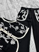 Conjunto de chaleco y pantalón color crudo con bordados de lentejuelas plateadas. El chaleco es sin mangas y el pantalón es de corte recto.