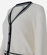 Cardigan de punto color marfil con escote en V, manga larga y cierre frontal de botones. Presenta ribetes acanalados en azul marino y verde en el cuello, puños y ruedo.