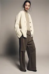 Chaqueta de punto de lana con cuello en pico, manga larga y cierre frontal con botones oscuros. Presenta un diseño de tejido grueso y holgado.