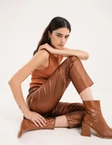 Pantalón negro estilo jeanero confeccionado en gabardina elastizada con terminación metalizada, pierna recta con largo por arriba del tobillo, cierre delantero y botón.