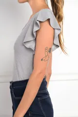 Remera plateada de punto, con cuello redondo y mangas cortas con volados.