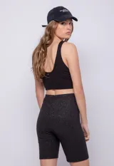 Calza ciclista negra de tela brillante con textura acanalada.