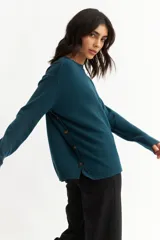 Sweater azul petróleo de tejido de punto, con cuello redondo y botones decorativos en los laterales.