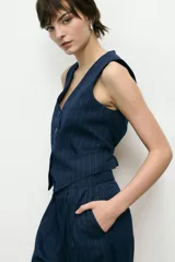 Chaleco azul marino a rayas verticales, con cuello en V y cierre frontal con botones.