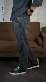 Pantalón de jean con corte recto y acabado lavado en color gris oscuro. Presenta cierre frontal con botón y bolsillos laterales.