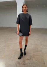 Vestido corto de satén color gris oscuro, con cuello redondo, mangas cortas y diseño recto. Cuenta con cierre de cremallera en la parte posterior y forro interior.